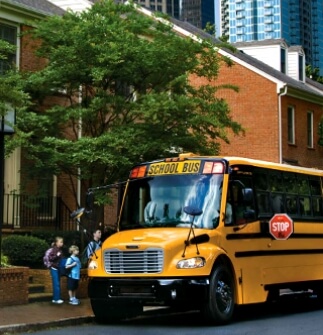 School bus parked in front of school with kids waiting to get on